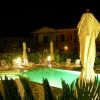 Piscina illuminata di notte con sdraio e ombrelloni chiusi.