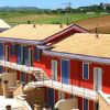 Edificio a due piani di colore rosso con balconi affacciato su paesaggio collinare.