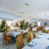 Ristorante con tavoli apparecchiati, sedie in legno e piante decorative.