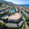 Vista aerea su un complesso turistico con piscina e anfiteatro vicino al mare.