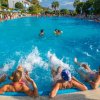 Persone in piscina fanno esercizi con schizzi d'acqua, mentre altre nuotano.