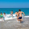 Persone corrono verso il mare turchese sulla spiaggia.