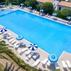 Piscina rettangolare con lettini e ombrelloni blu e bianchi tutt'intorno.