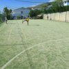 Un campo da calcetto all'aperto con rete di protezione, persona che calcia la palla.