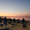 Spiaggia al tramonto con ombrelloni chiusi.