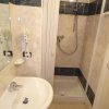 Bagno con doccia e lavandino bianchi.