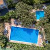Vista dall'alto di due piscine circondate da alberi e ombrelloni a righe.