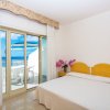 Una camera con letto matrimoniale, fiori sul comodino e vista mare.