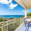 Balcone con tavolino e due sedie affacciato sul mare, vista panoramica su palme e tetti.