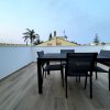 Terrazza con tavolo nero e sedie, con vista sulle palme.