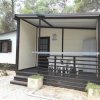 Bungalow con veranda coperta, tavolo e sedie bianche.