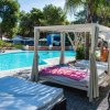 Una piscina con lettini, gazebo con tende bianche e un'atmosfera rilassante.