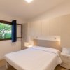 Camera con letto matrimoniale, mobili chiari e finestra aperta su giardino.