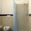 Bagno con doccia angolare, tenda azzurra e water.