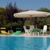 Piscina luminosa con lettini colorati e ombrellone bianco, immersa nel verde.