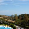 Piscina con vista su colline verdi e mare in lontananza.