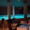 Piscina interna con illuminazione blu, tavoli e sedie intorno.