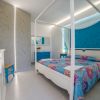 Camera da letto con letto a baldacchino colorato, mobili bianchi e tocchi di blu.