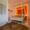 Camera da letto con letto a baldacchino bianco, parete arancione illuminata e tappeto marrone.