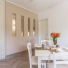 Sala da pranzo moderna con tavolo bianco e fiori arancioni.