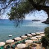Spiaggia con ombrelloni bianchi e mare azzurro, vista di un'isola in lontananza.