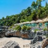 Spiaggia con rocce e ombrelloni verdi.