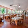 Interno di ristorante con tavoli apparecchiati di arancione e bianco, e grandi finestre luminose.