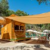 Chiosco in legno sulla spiaggia con tavoli e sedie, ombreggiato da teli.