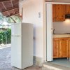 Una cucina all'aperto con pensilina, frigorifero bianco e mobili in legno.