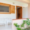 Due sedie bianche davanti a una veranda con finestre e porta in legno, vicino a un giardino.