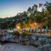 Tavolo lungo all'aperto su una terrazza rocciosa, illuminato al tramonto vicino al mare.