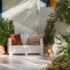 Angolo relax con divanetto bianco e piante in vaso su una terrazza.
