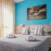 Letto matrimoniale con cuscini a righe, parete blu, quadro sopra il letto e luci a parete.