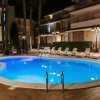 Piscina illuminata di notte, circondata da lettini.