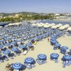 Spiaggia con ombrelloni blu e bianchi.