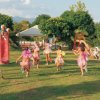 Bambini in costumi colorati giocano in un parco con scivoli e altalene.