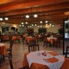 Interno di un ristorante con tavoli apparecchiati e soffitto in legno.
