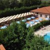 Piscina con ombrelloni, vegetazione intorno.