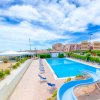 Piscina con scivolo accanto al mare e palazzi.