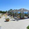 Area esterna con gazebo e sedie gialle, circondata da piante e vista mare.