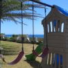 Altalene e scivolo in un giardino, vista mare sullo sfondo.