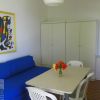 Interno semplice con divano blu, tavolo bianco, quattro sedie e un quadro colorato alle pareti.