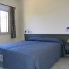Una stanza d'albergo con letto matrimoniale coperto da una trapunta blu e una finestra.