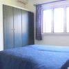 Camera con letto matrimoniale blu, finestra, armadio e tende a quadri.