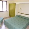 Stanza d'albergo con letto matrimoniale, divano e armadio verde.