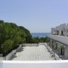 Vista panoramica di un terrazzo con alberi e mare in lontananza.