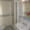Bagno con doccia, lavandino e specchio illuminato. Fiori sul ripiano.