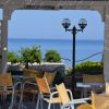 Gazebo con sedie gialle vista mare, lampione nero al centro.