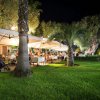 Giardino di un ristorante con tavoli illuminati e palme.