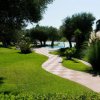 Sentiero curvo tra prati e alberi, vicino a una piscina.